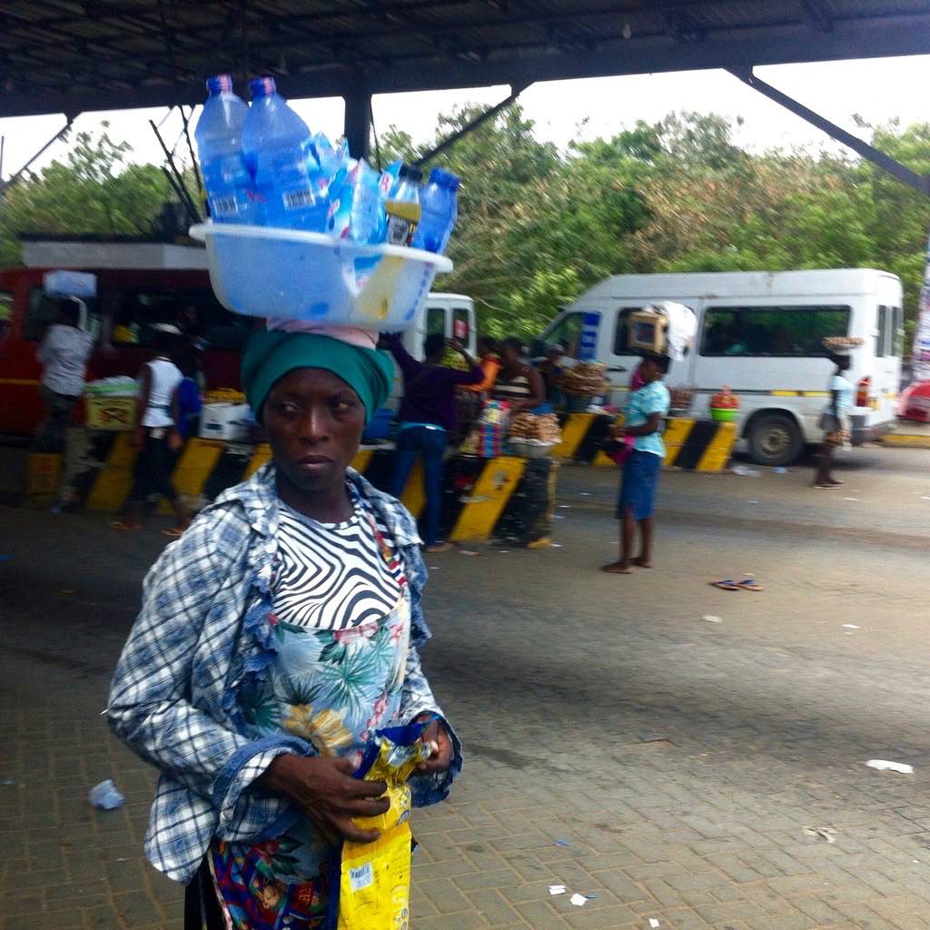 Woman roadside hawking bottled water in Accra, Ghana. #JujuFilms