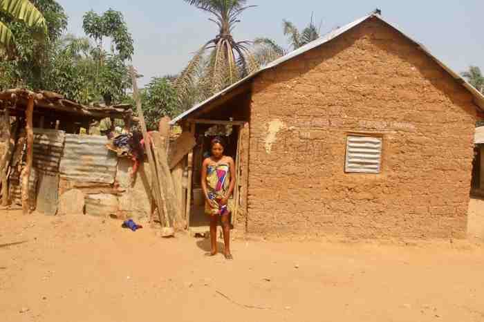 Eggon woman wearing traditional wrapper standing in front of her red mud hut, Langa Langa Village, Nasarawa State, Nigeria. #JujuFilms